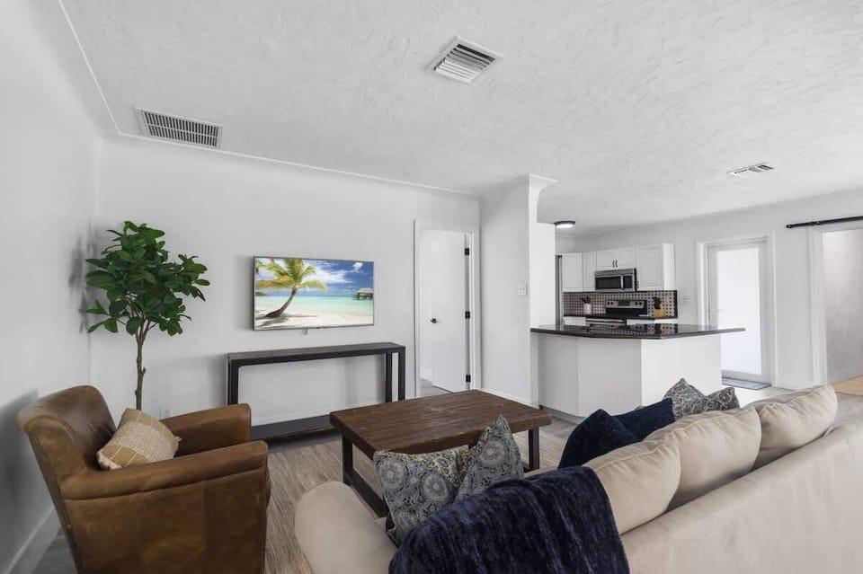 Cozy and bright living room with comfy seating and smart TV — perfect for relaxing after a beach day.