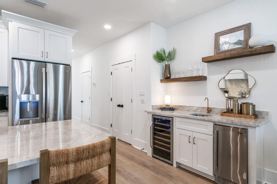 A wet bar in the corner of the kitchen features a wine cooler, ice maker, and sink.