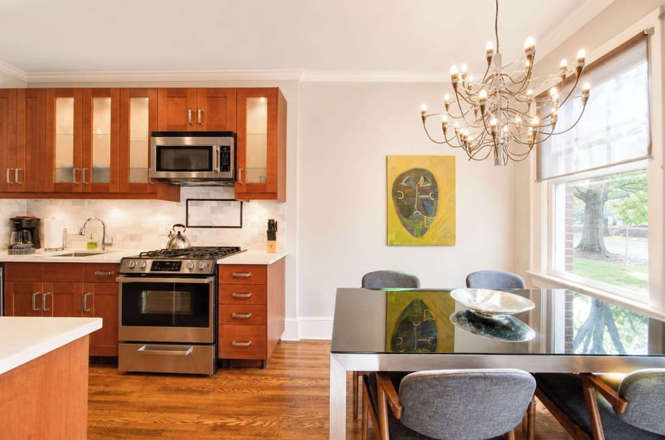 Bright and elegant, this dining space features a glass-top table, comfortable seating, and a statement chandelier. Natural light and clean design make it ideal for meals or gathering together.