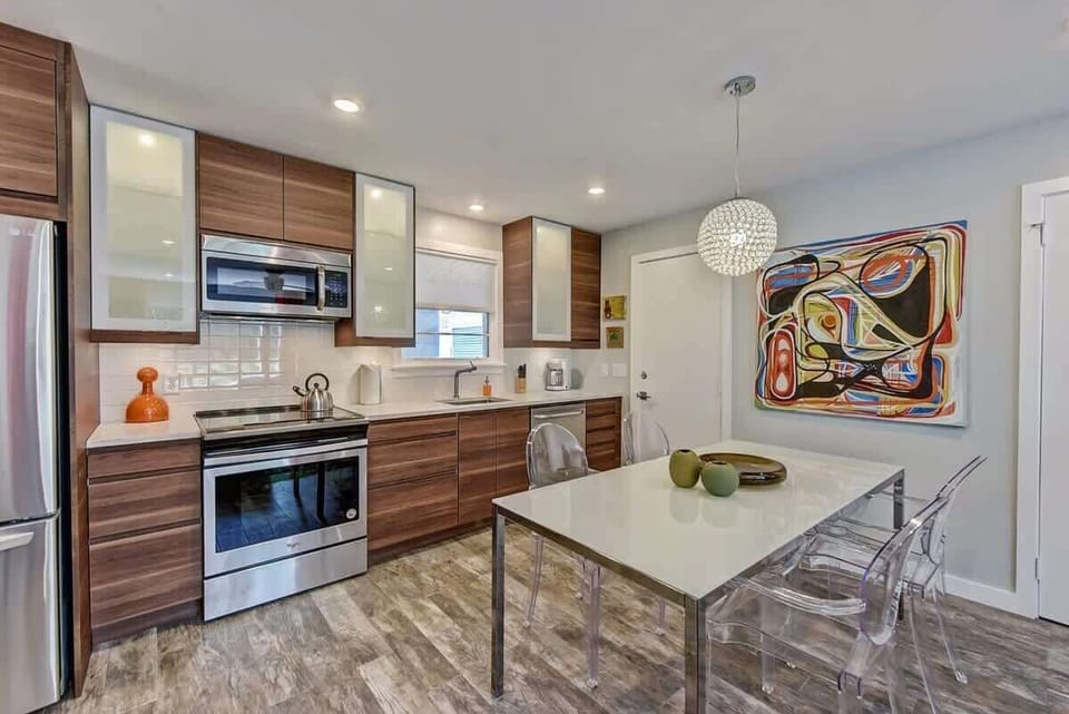 The open-concept design pairs a chef-ready galley kitchen with an intimate dining space, anchored by vibrant abstract art and a statement pendant light.
