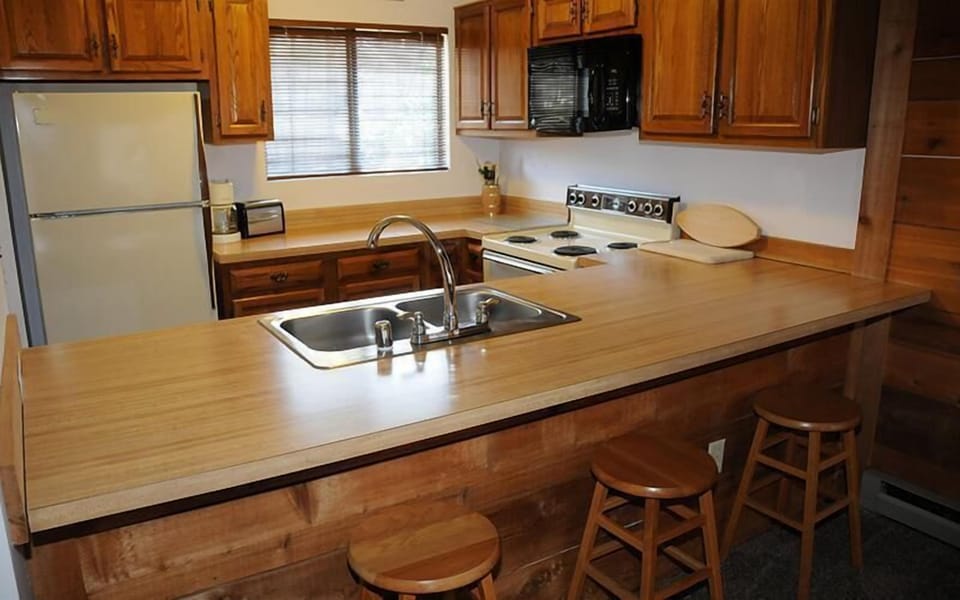 Fully equipped kitchen with breakfast bar seating and adjacent dining area.
