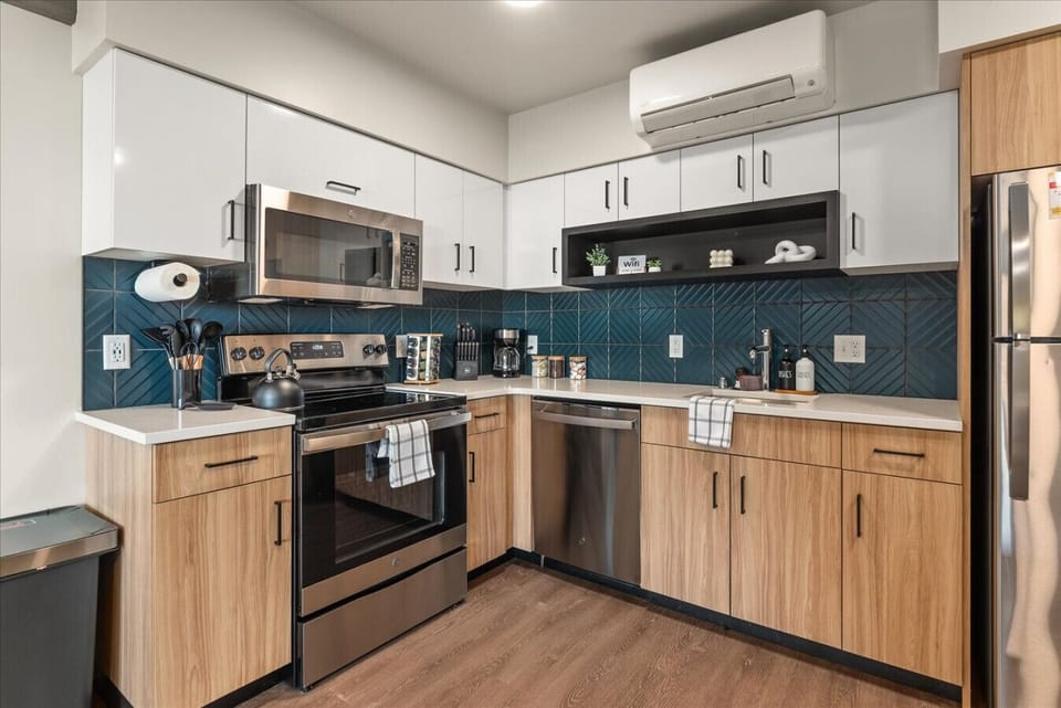 - Cook up your favorites in a chef-ready kitchen with stainless steel appliances   - Blue geometric backsplash adds a modern touch to wood and white cabinetry   - Stocked with utensils, pots, and coffee essentials for your daily convenience