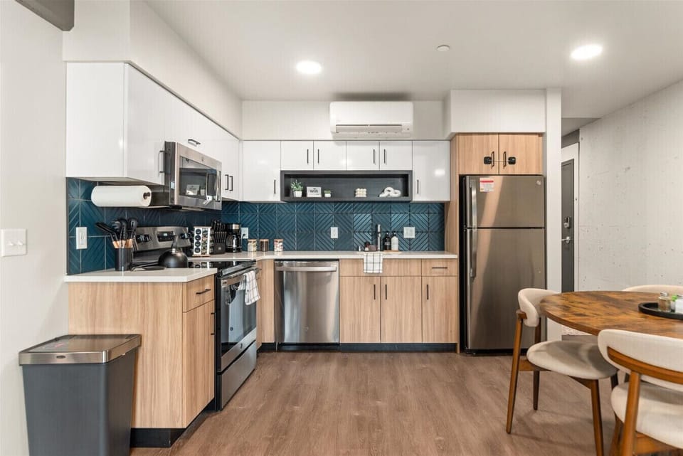 - Cook with ease in a modern kitchen featuring stainless steel appliances and sleek finishes   - Enjoy stylish two-tone cabinetry and deep blue geometric backsplash design   - Fully stocked with cookware, coffee maker, and essentials for a comfortable sta
