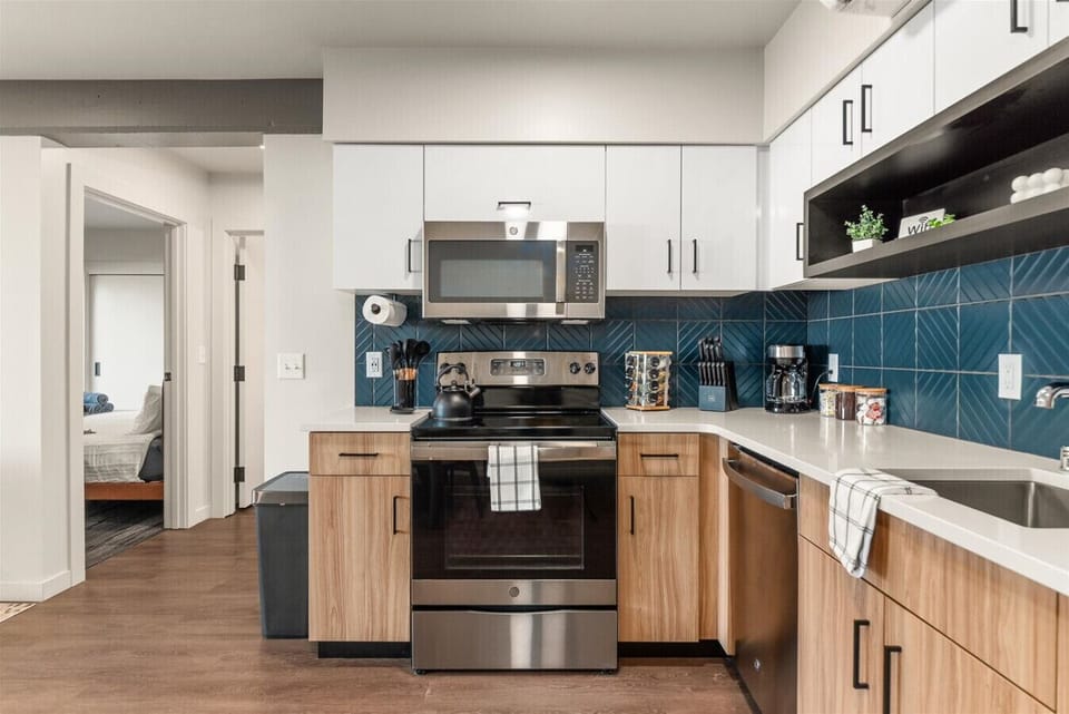 - Fully equipped kitchen with stainless steel appliances and sleek design details   - White and wood cabinetry pairs beautifully with deep blue textured backsplash   - Everything you need for easy cooking, morning coffee, or evening meals