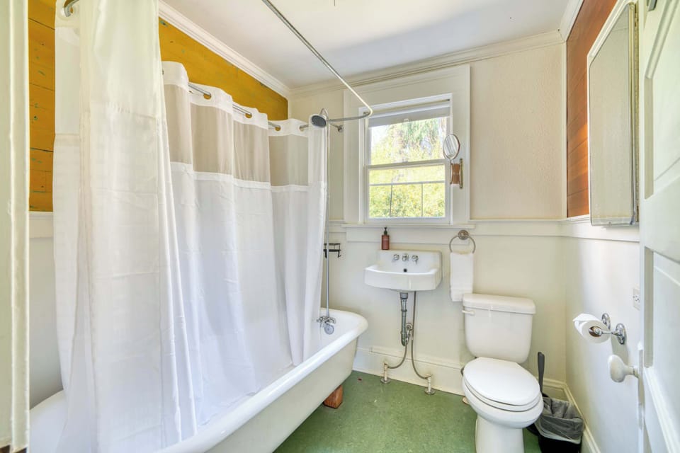 Bathroom with clawfoot tub/shower, sink and toilet.