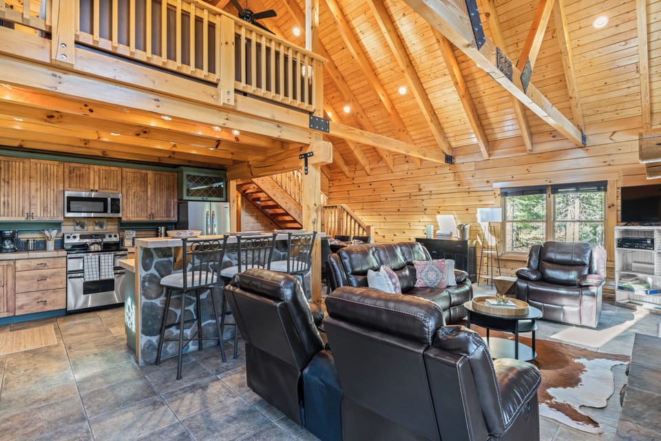 Loft-style view of the living area and kitchen with high wood-beam ceilings.