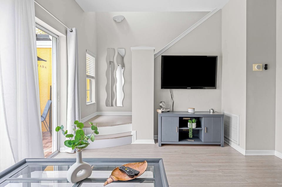 Modern living area with a wall-mounted television and natural light from sliding glass doors.