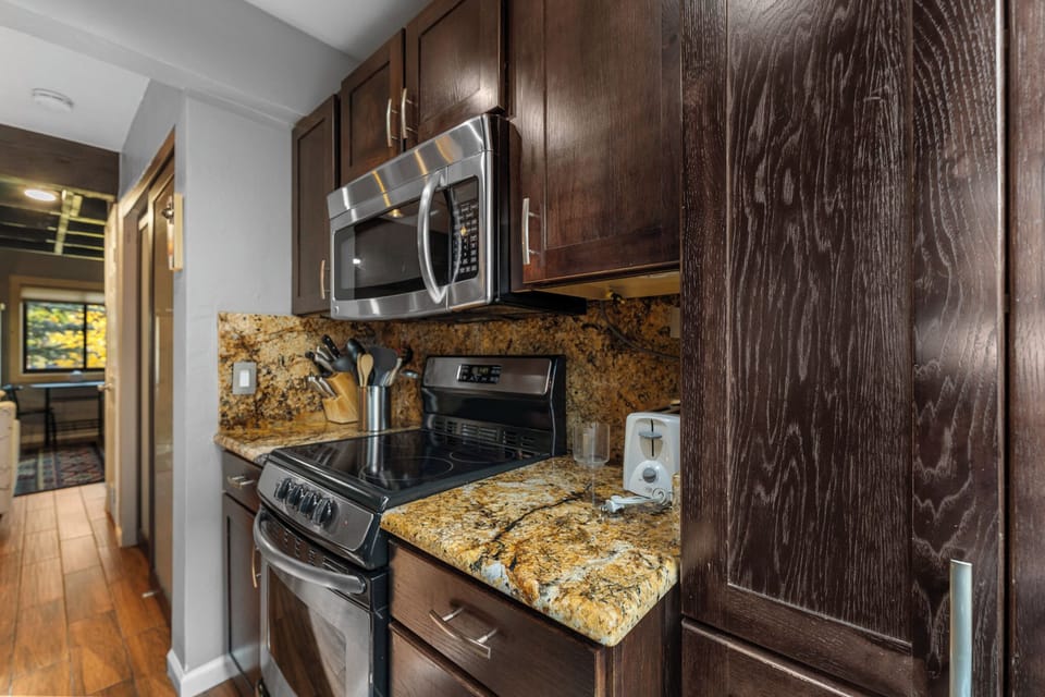 Your fully equipped kitchen features granite countertops, stainless appliances, and rich wood cabinetry—perfect for preparing meals during your stay.