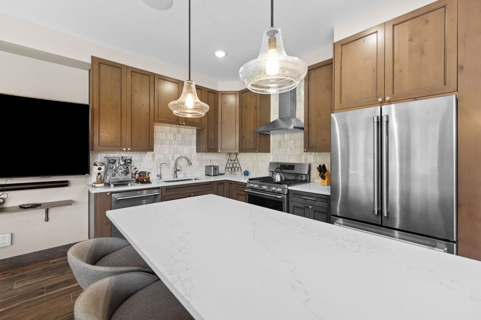 Your gourmet kitchen awaits with sleek stainless appliances, warm wood cabinets, and a spacious island perfect for cooking memorable meals together.