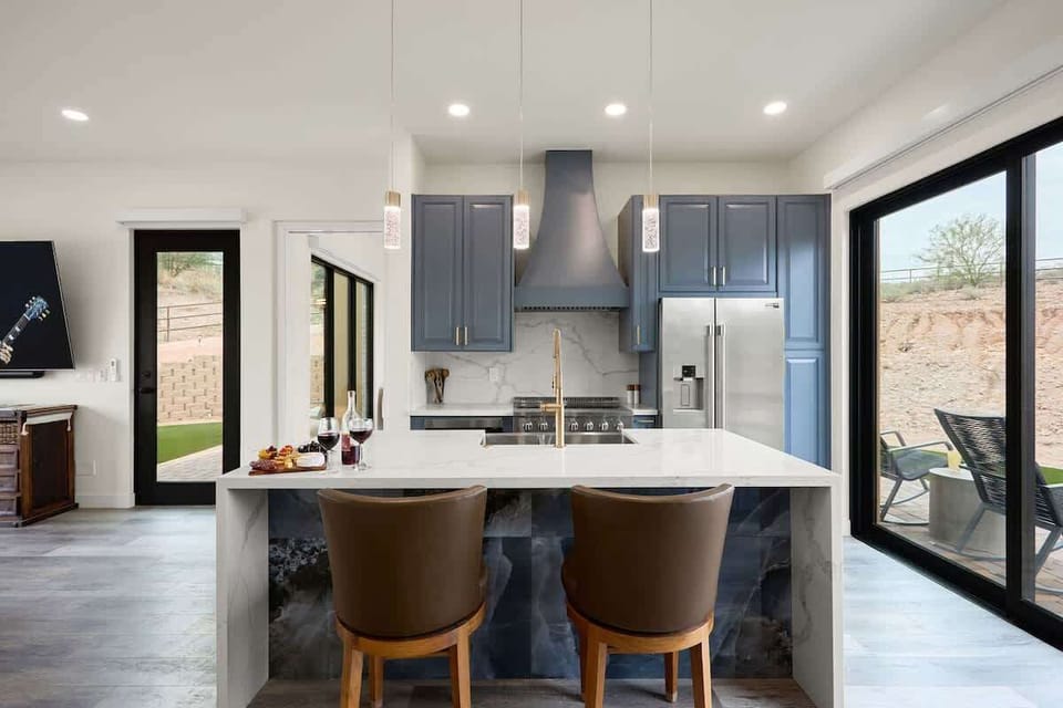 Fully equipped kitchen with stainless steel appliances, a sleek kitchen island with a breakfast bar for casual seating for 2.