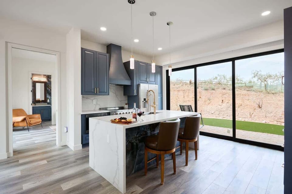 Fully equipped kitchen with stainless steel appliances, a sleek kitchen island with a breakfast bar for casual seating for 2.