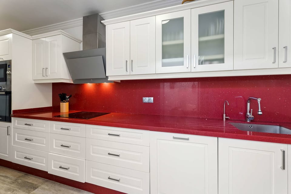 Bold meets practical in this fully equipped kitchen ❤️‍🔥 Crisp white cabinetry contrasts beautifully with the deep red countertops — a space made for cooking, sharing and creating delicious memories. 🍷🥘