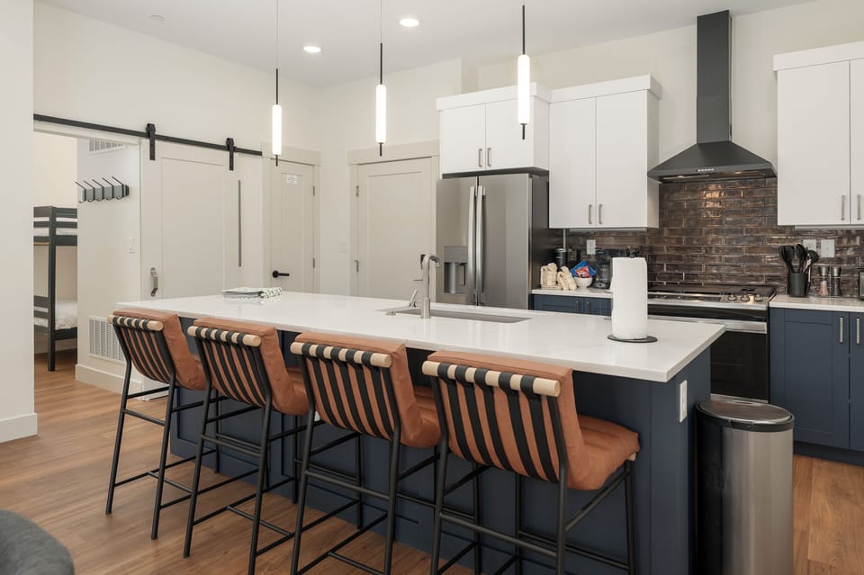 Gather around your gorgeous kitchen island for morning coffee or evening cocktails, with stylish leather bar stools and modern pendant lighting creating the perfect gathering spot.