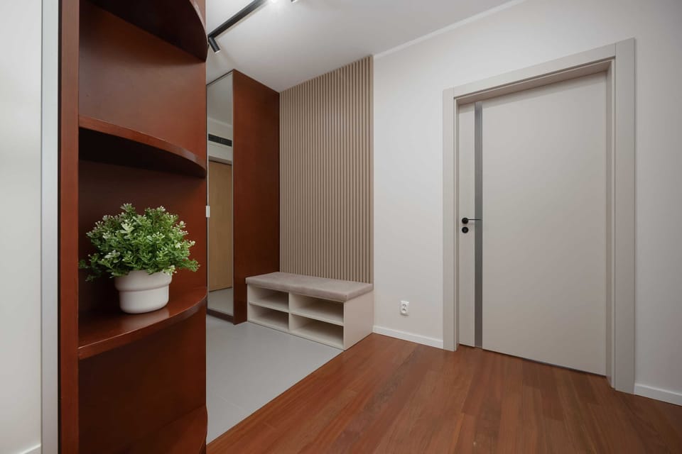 A hallway with built-in wardrobes, wooden floors, and warm lighting providing both functionality and elegance.
