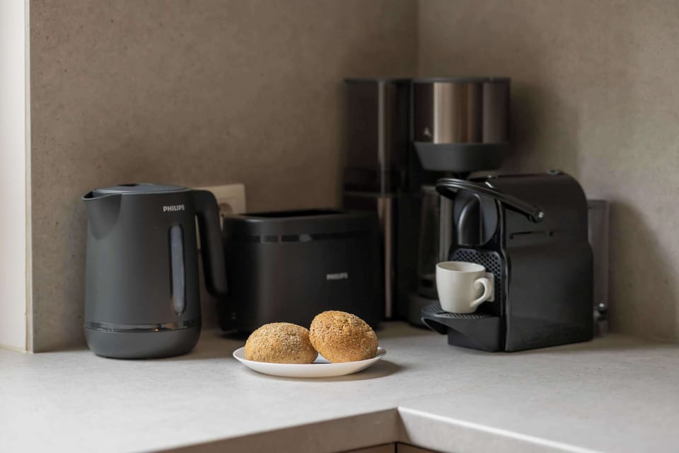 A cozy kitchen corner featuring a coffee machine, toaster, and a breakfast setup with fresh bread.