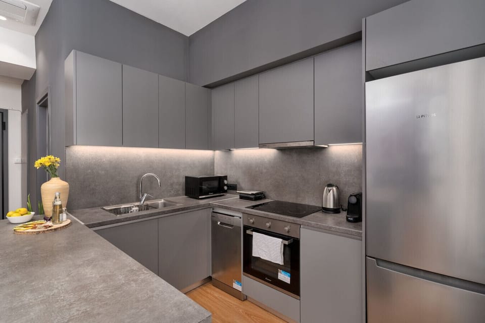 Contemporary grey kitchen with full amenities, infused with Mediterranean warmth and minimal precision.
