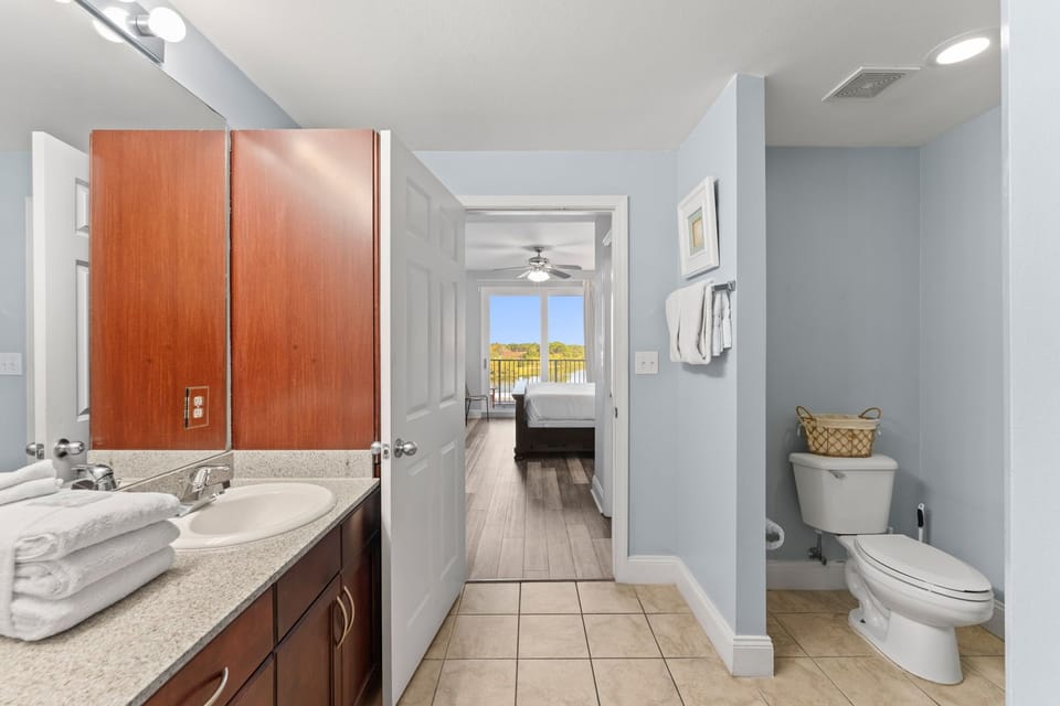 view from the bathroom into a bedroom with natural light and a balcony