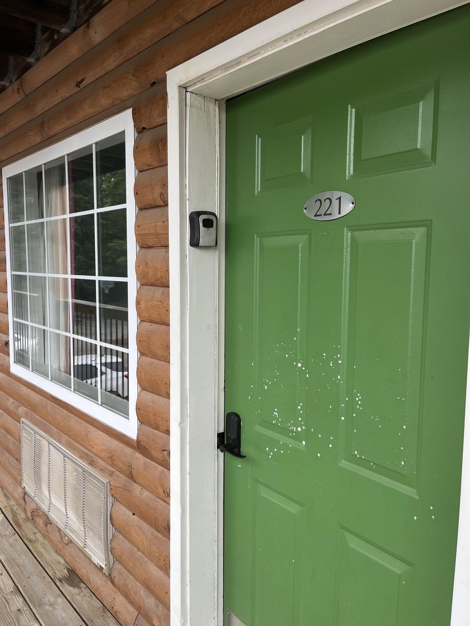 Charming entryway with vibrant green door and cozy wood siding