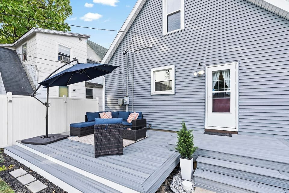Inviting backyard deck with cushioned seating and a large umbrella, perfect for relaxed conversations, morning coffee, or unwinding after a day out.