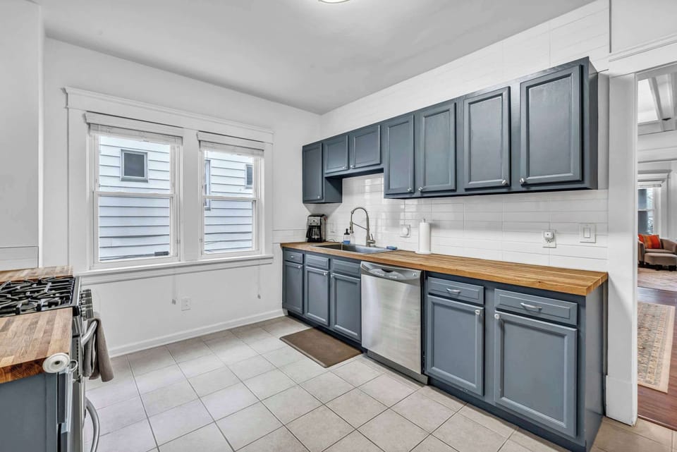 Bright and spacious kitchen featuring modern blue cabinetry, butcher-block counters, and stainless appliances — perfect for preparing home-cooked meals in style.