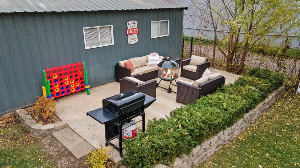 The fully fenced backyard features an 18x27 patio with a hot tub, sauna, and dining set, a private fire pit area, gas grill, outdoor games, rocker swing, basketball hoop, and pickleball net.