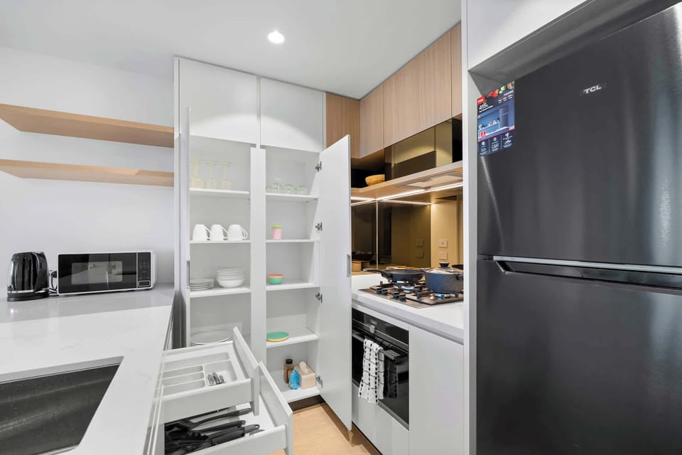 Fully equipped kitchen featuring oven, fridge, microwave, kettle, and complete dinnerware set
