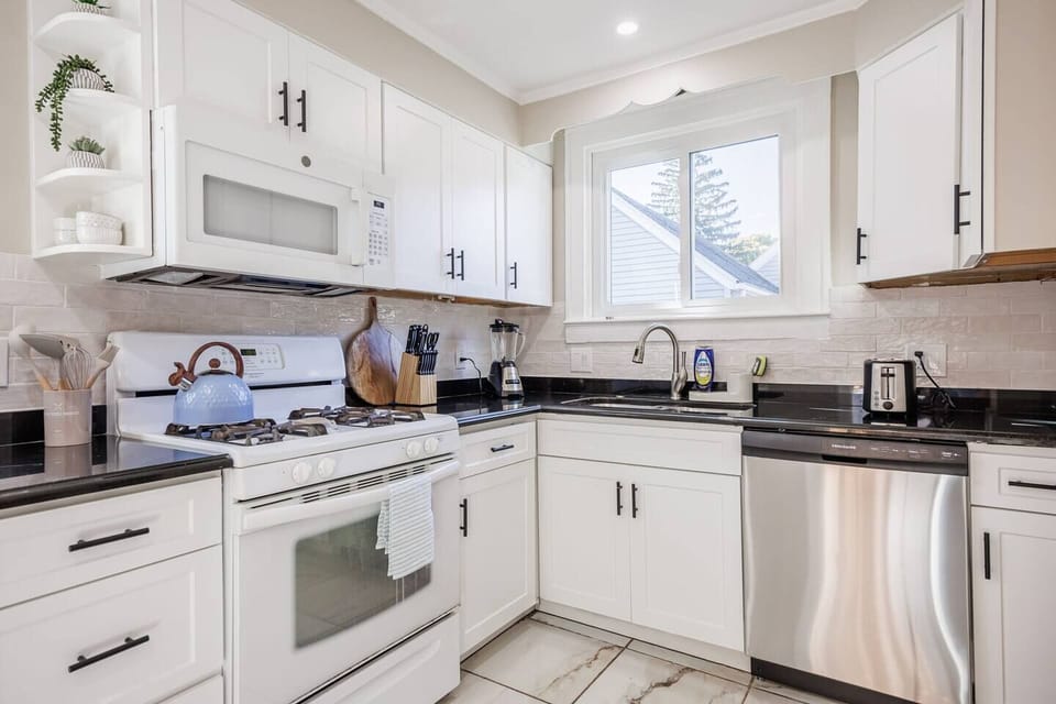 Elegant fully stocked kitchen with modern appliances, cookware, and dining essentials.