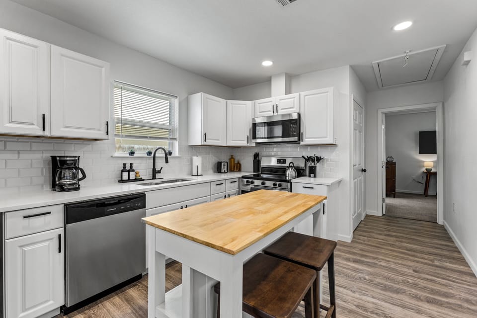 Fully equipped kitchen with stainless steel appliances and island seating.
