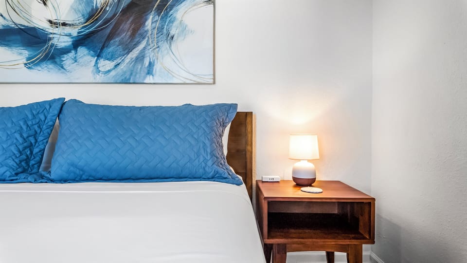 Cozy bedroom with calming blue tones, soft bedding, and modern artwork.