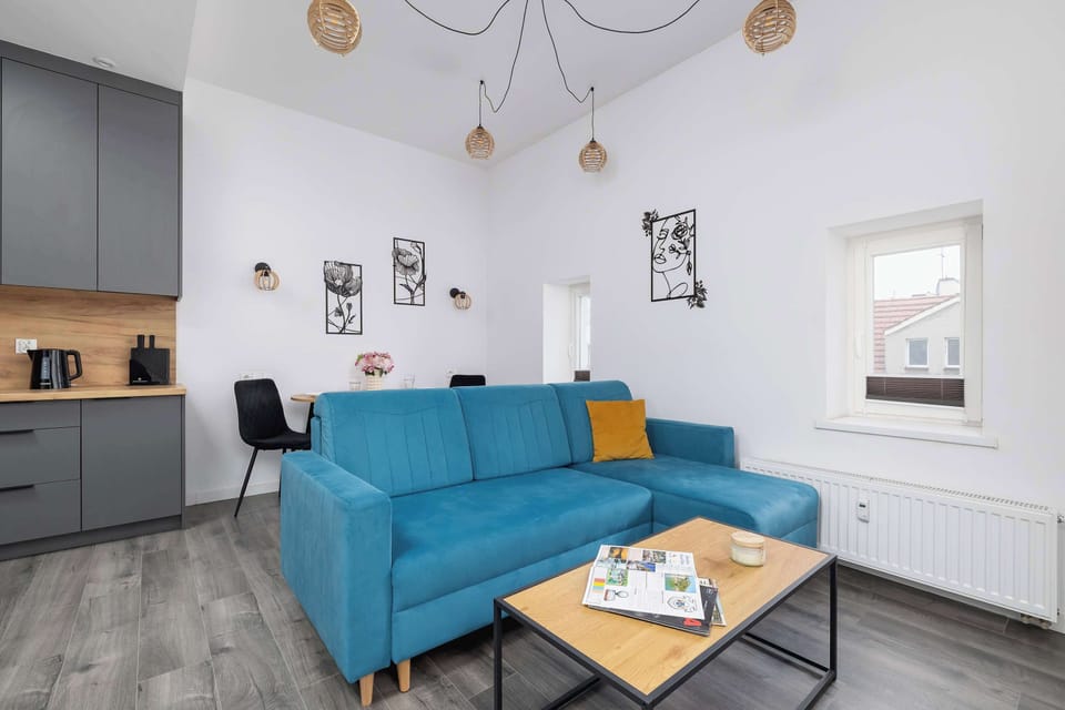 Another angle of the living area showing the blue sofa and the entrance to the kitchenette. The room has stylish lighting and decorative elements.