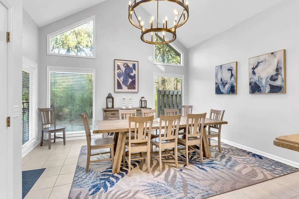Gather around this elegant dining table where natural light streams through tall windows, creating the perfect setting for memorable meals together.