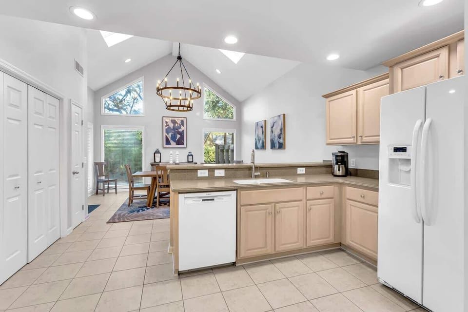 Your bright, fully-equipped kitchen features vaulted ceilings, modern appliances, and warm wood cabinetry—perfect for preparing meals while natural light streams in.