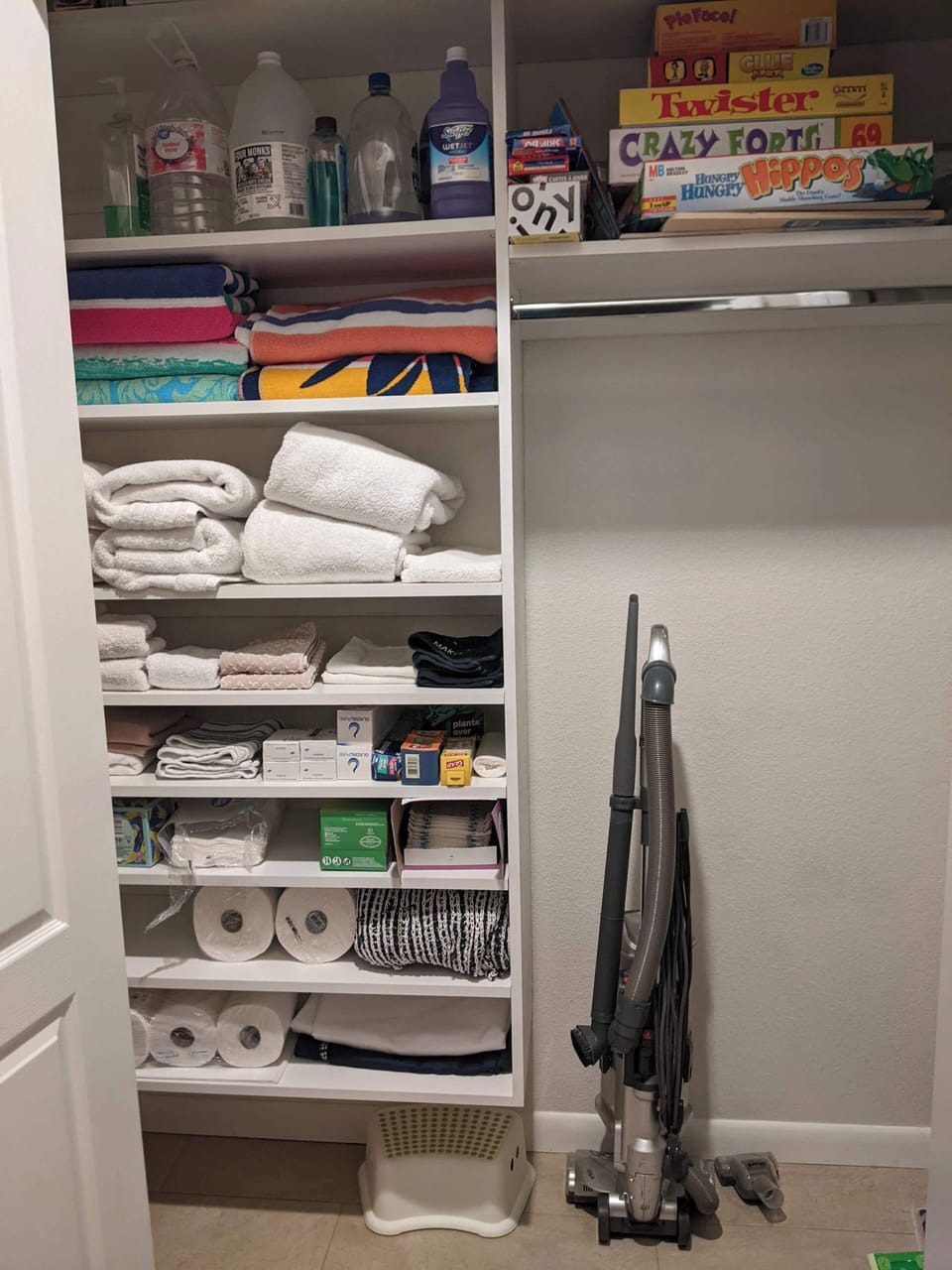 Hall closet with plenty of towels, board games, vacuum, supplies and mop
