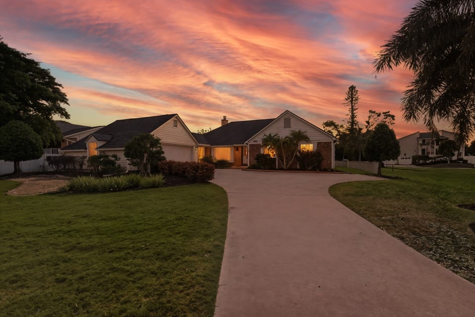Take in the whole retreat from above — sprawling screened pool, lush palms, and a circular drive framing your private Florida escape