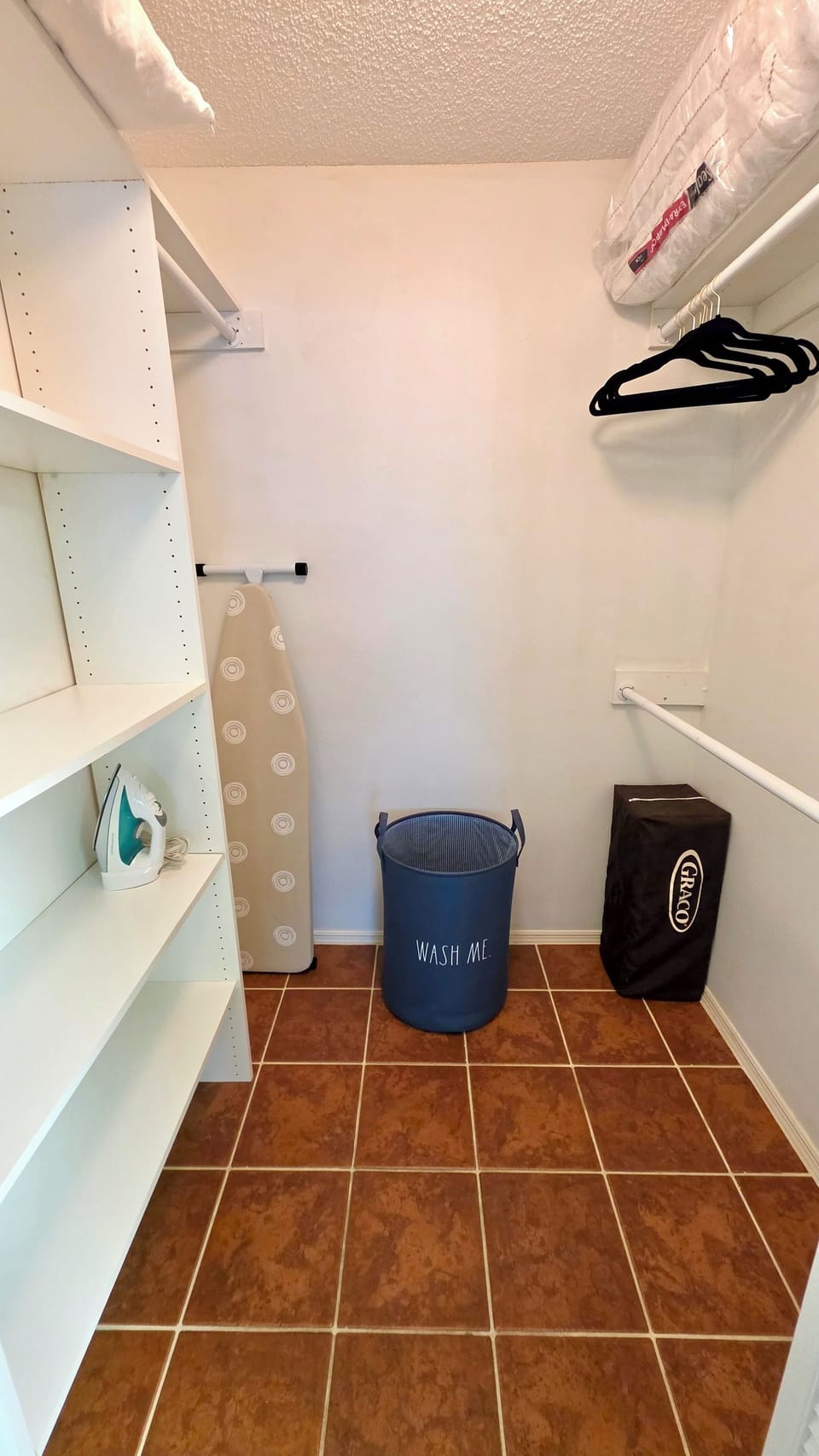 Laundry and utility area with ironing board, laundry basket, and storage