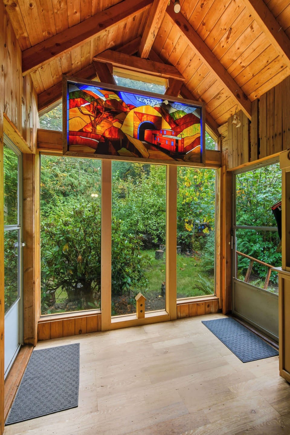 Sunroom entry framed by stained glass and forest windows