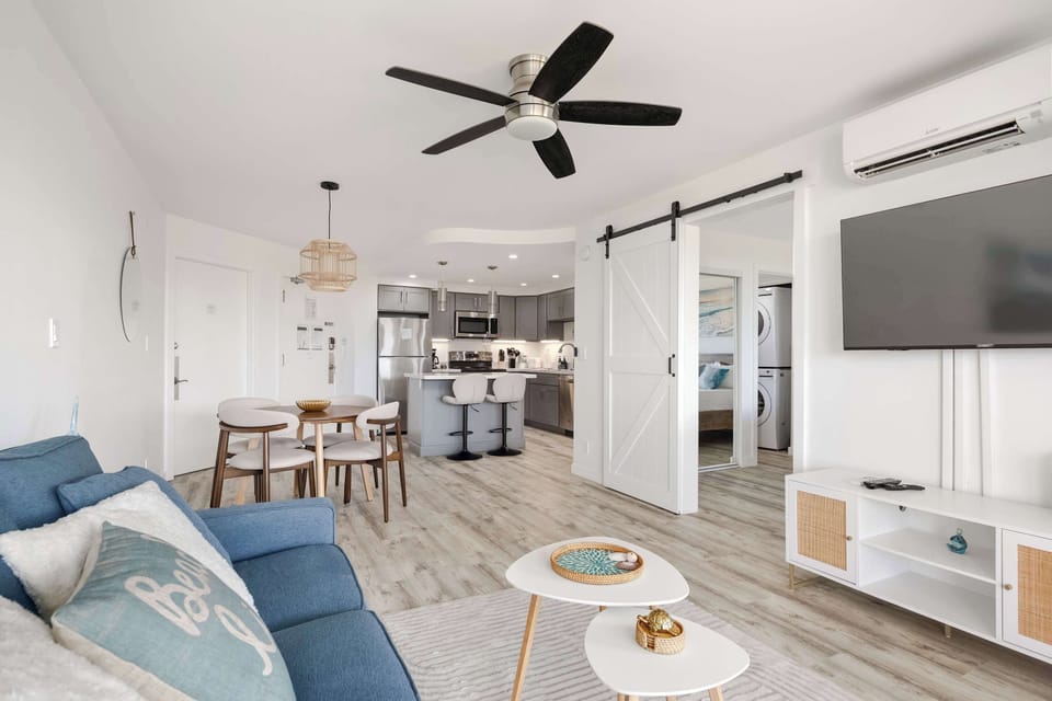 Relax in your open-concept living space, complete with a 50" TV, stylish dining area, and seamless flow into a fully equipped modern kitchen.