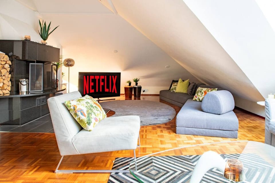 A comfortable loft lounge with modern seating, a fireplace, and a large TV — perfect for relaxing after a day out in the city.