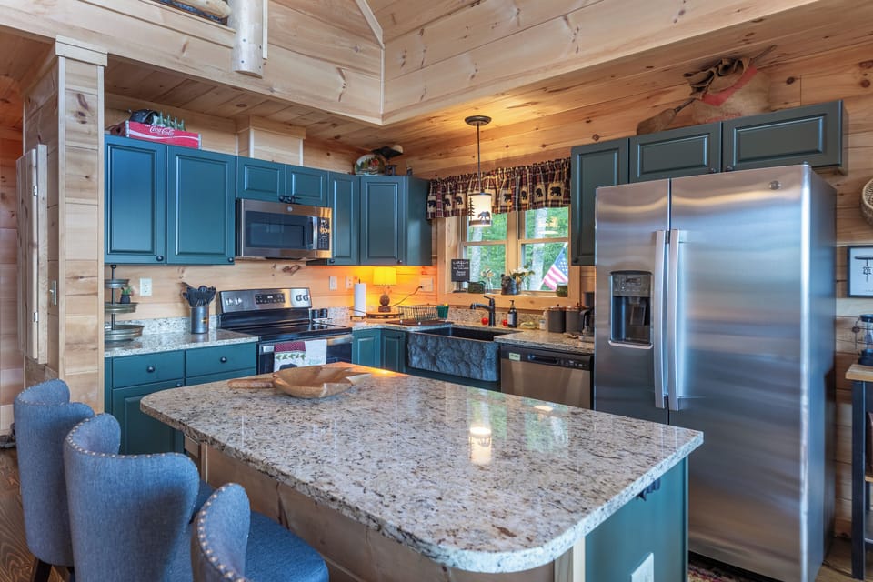 Enjoy meals in this charming cabin kitchen featuring granite countertops, stainless steel appliances, and forest views right from the sink. Perfectly blending rustic style with modern comfort for your mountain getaway.