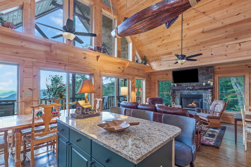 Gather in this stunning great room with soaring ceilings, a stone fireplace, and wall-to-wall windows framing breathtaking mountain views. Perfect for relaxing, dining, or entertaining in rustic luxury at your unforgettable cabin retreat.