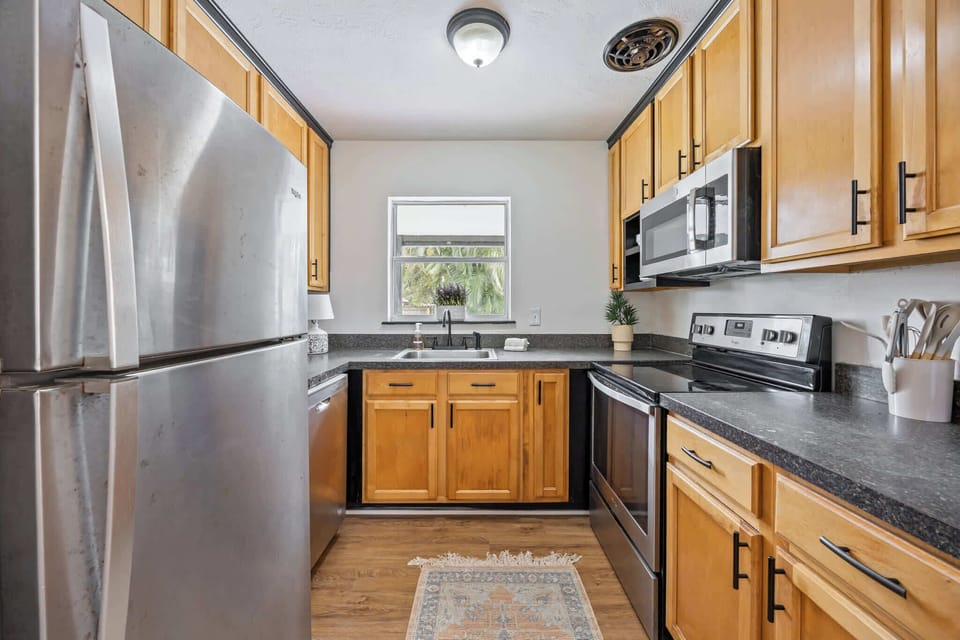 Compact kitchen with stainless steel appliances and natural wood cabinets.