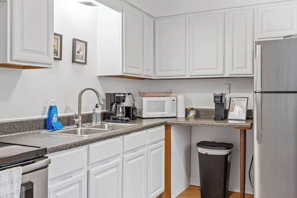 Compact kitchen with white cabinetry and essential appliances for convenient cooking.