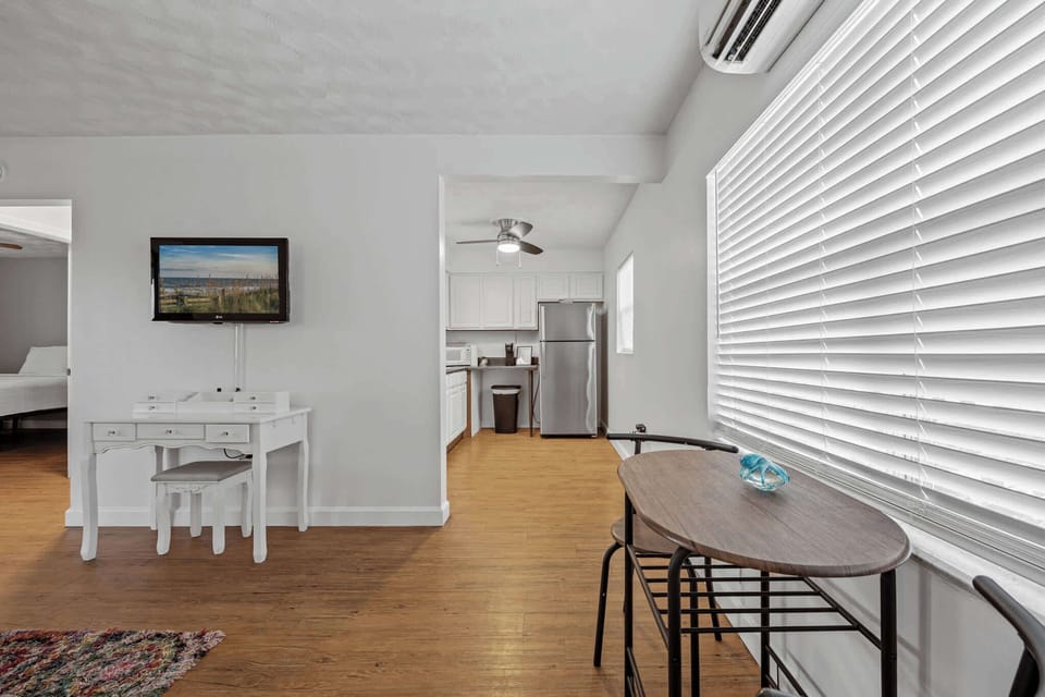 Bright living area with a compact kitchen and natural light from large window blinds