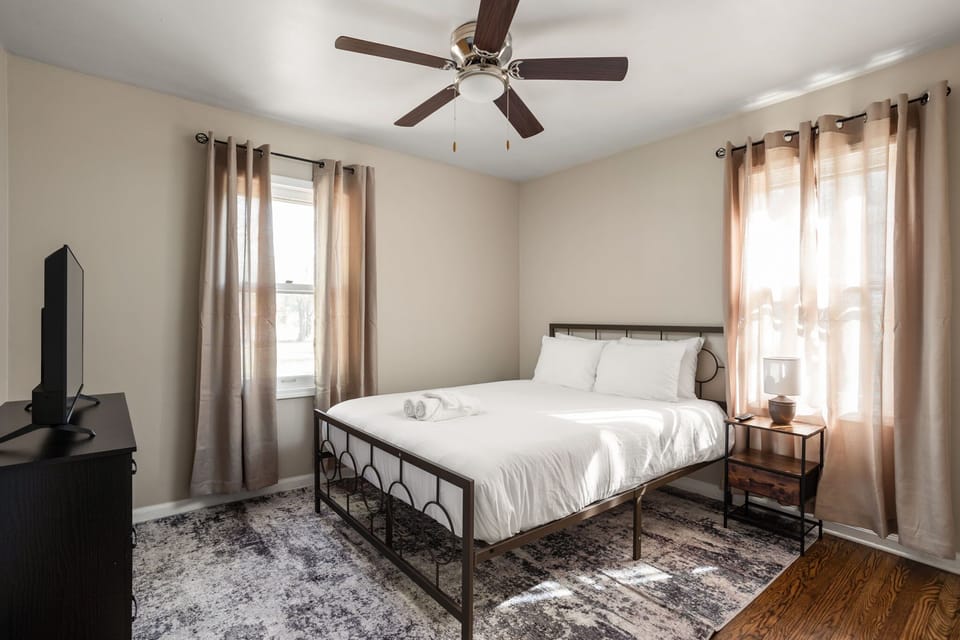 Queen Bed with a TV, premium linens, and warm decor.