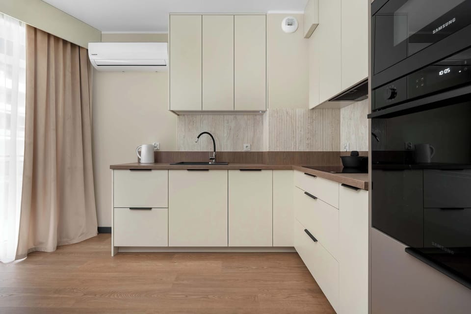 Modern kitchen with sleek white cabinets, oven, and induction hob perfect for home cooking.