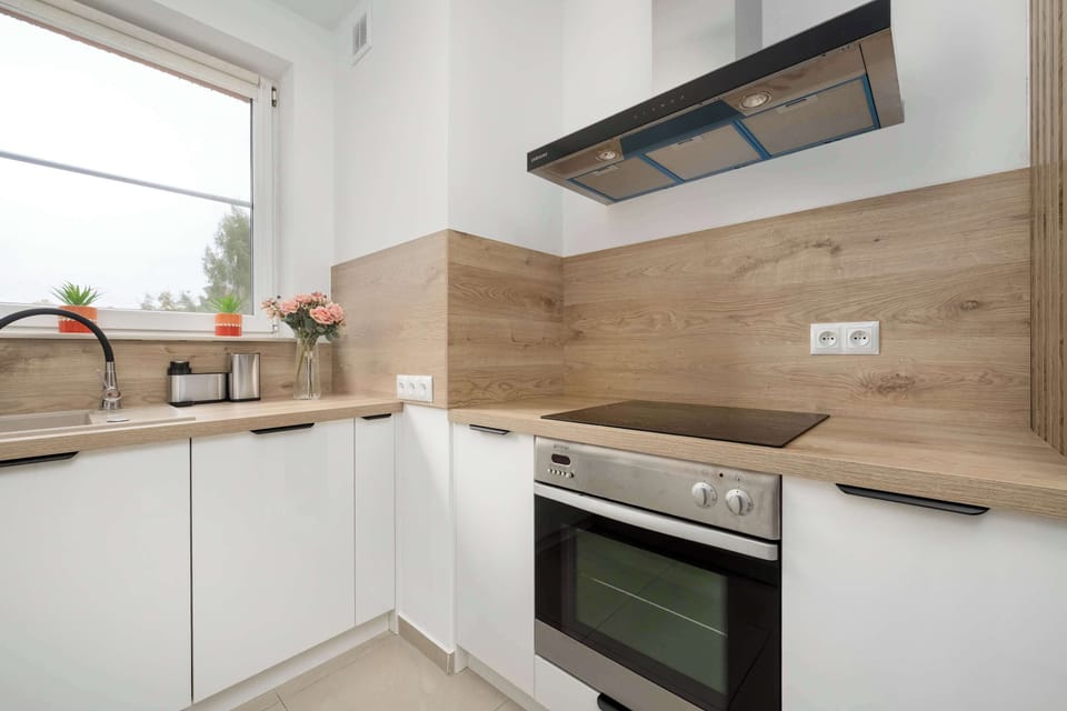 A modern kitchen with white countertops and appliances like a microwave, stove, and refrigerator.