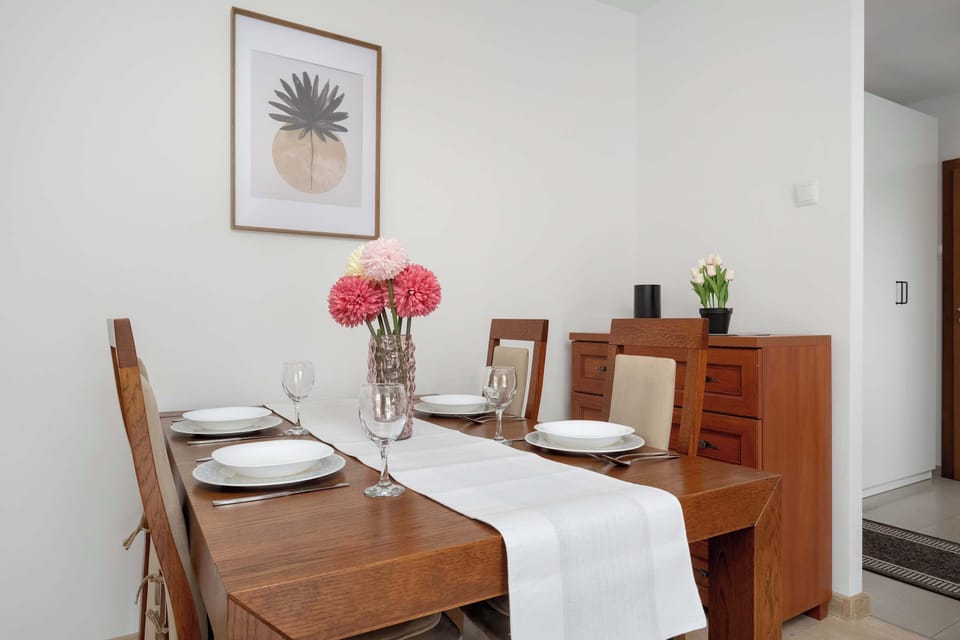 A dining area with a wooden table set for a meal, bright natural light coming in through the windows.