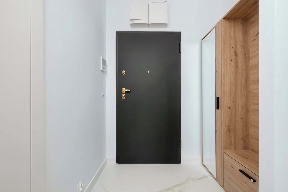A modern entrance with contrasting wood and black accents welcomes guests with elegance and simplicity.