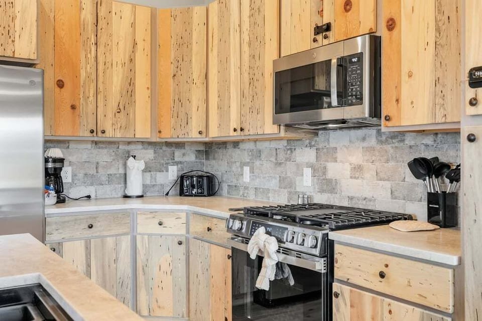 Your rustic kitchen at 128 GCR 4034 features modern appliances amidst charming reclaimed wood cabinets, perfect for preparing memorable mountain meals together.
