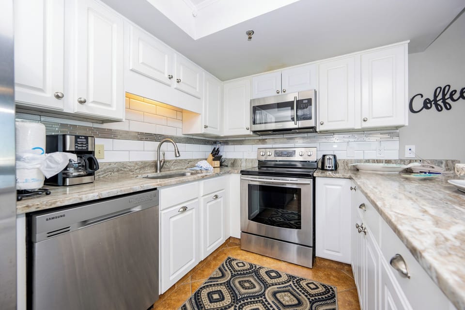 Elegant kitchen featuring granite countertops, stainless appliances, and a coffee station for your morning brew